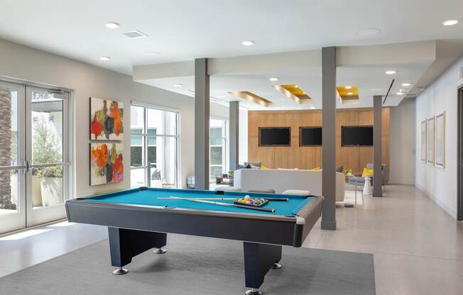 A pool table in a room with a wooden cabinet and a painting on the wall.