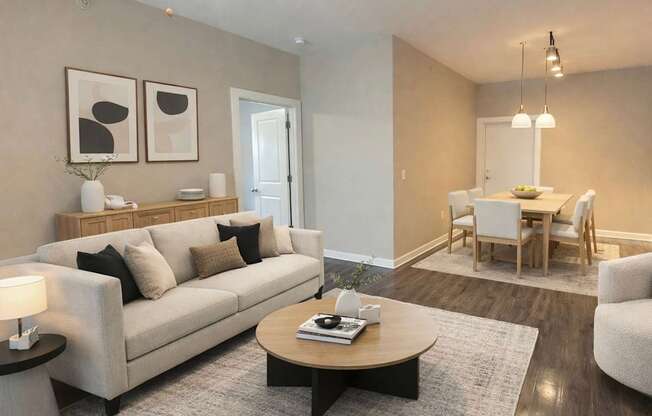 A living room with a beige couch, a coffee table, and a dining table with chairs.