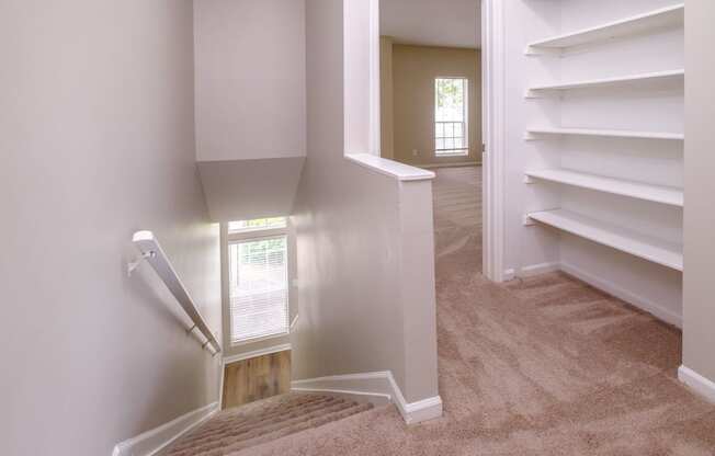 a hallway with white shelves and carpet