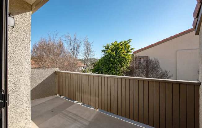 A balcony with a beige railing and a concrete floor.