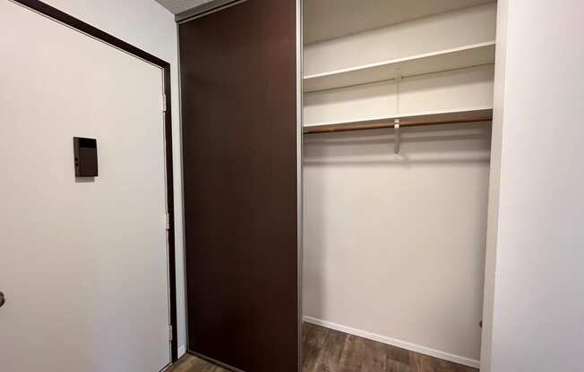 an empty room with a white wall and a brown door