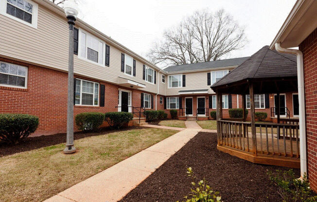 a courtyard with a wooden gazebo in front of a brick building