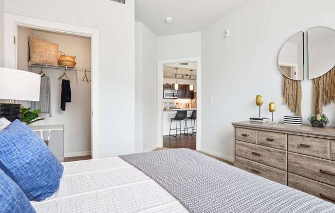 A bedroom with a large bed and a mirror on the wall. at Connect at First Creek Apartments, Denver, CO