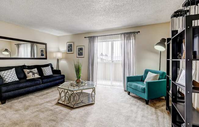 Living room with accent chairs and glass coffee table in Aurora Meadows two-bedroom.