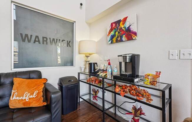 A living room with a black couch and a glass coffee table.