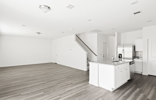 a kitchen and living room with white walls and wood floors