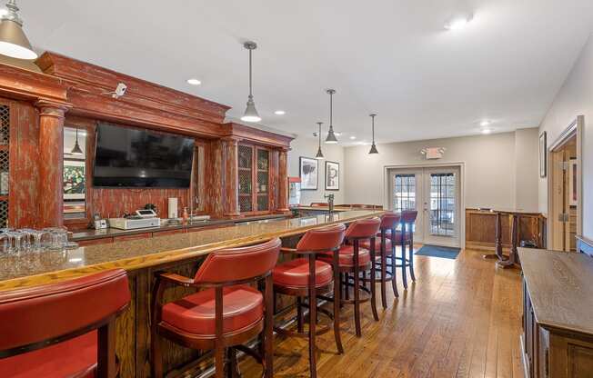 a bar with red chairs in a room with a television