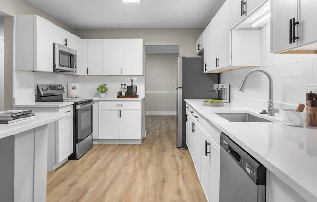 A modern kitchen with white cabinets and a wooden floor.