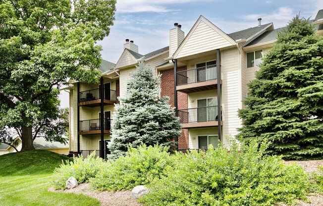 Apartment buildings with balconies and greenery in front.