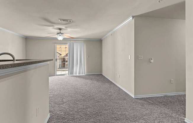 A spacious room with a ceiling fan and carpeted floor.