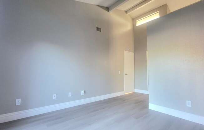 the living room and dining room of a house with white walls and wood floors