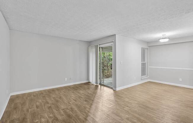 A room with wooden flooring and a sliding glass door leading to a garden.