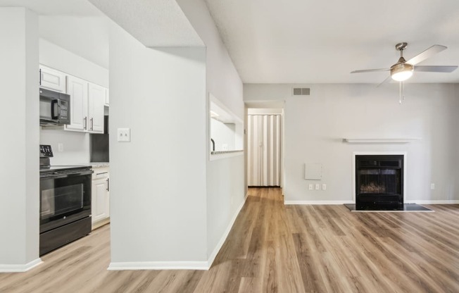 an empty living room with a fireplace and a kitchen