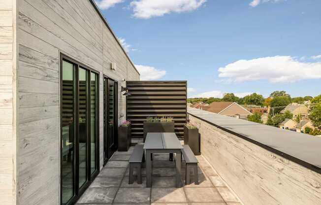 A modern balcony with a table and chairs overlooking a residential area.