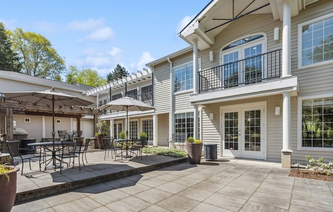 A patio area with a table and chairs is in front of a two-story apartments