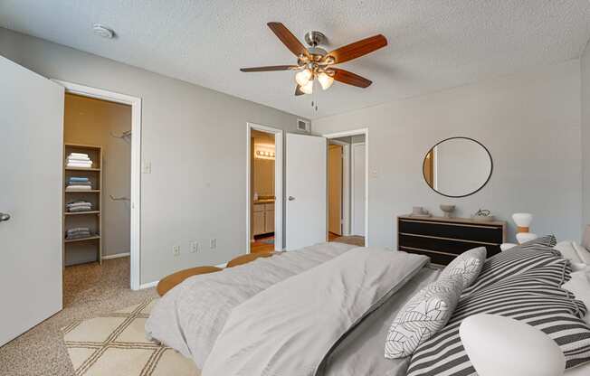 A bedroom with a bed, dresser, and a ceiling fan.