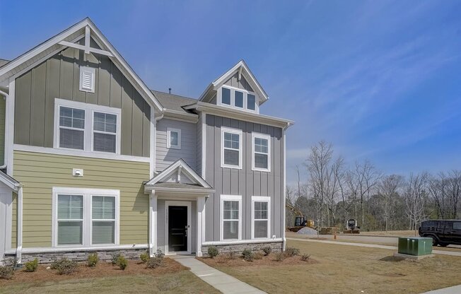 A two-story house with a green and grey exterior.