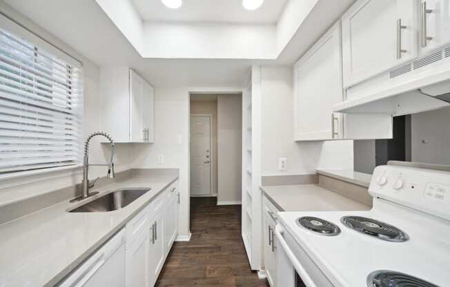 a white kitchen with white appliances and white cabinets at Woodlands of Plano in Plano, TX