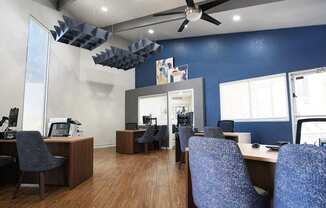 A room with blue walls and wooden floors has several chairs and desks arranged in it.
