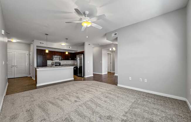an empty living room and kitchen with a ceiling fan