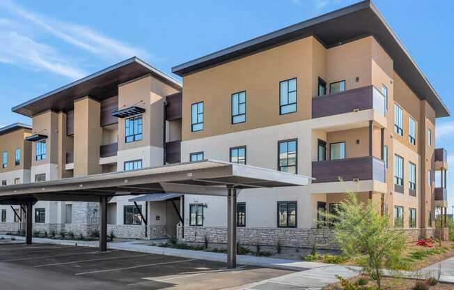 a large apartment building with an awning in front of a parking lotat Solace at Ballpark Village, Goodyear