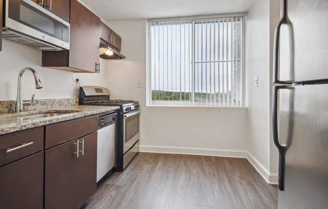an empty kitchen with stainless steel appliances and a window