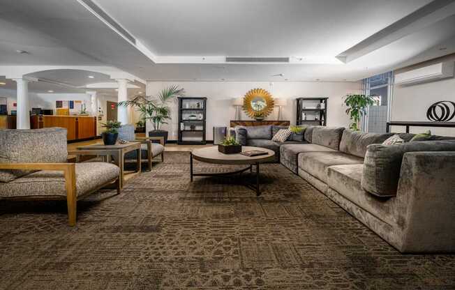 A living room with a patterned carpet and a variety of furniture including a sofa, armchair, and coffee table.