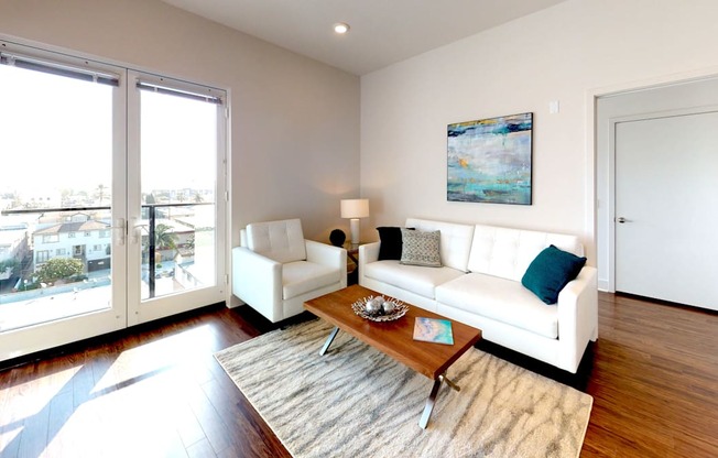 A living room with a white couch and a painting on the wall.
