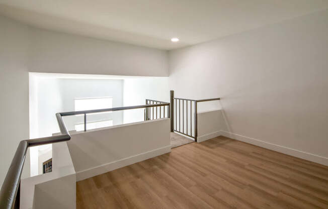 A room with wooden floors and a balcony with a metal railing.
