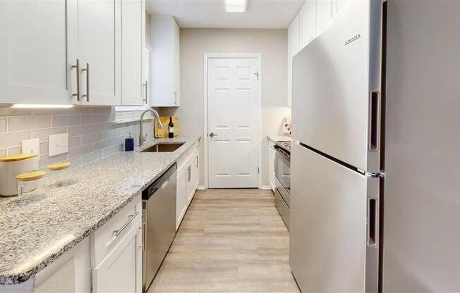 A kitchen with white cabinets and a granite countertop.