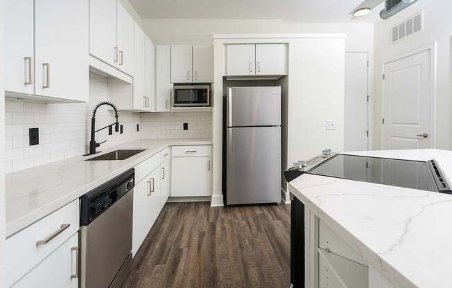 A kitchen with white cabinets and a stainless steel refrigerator.