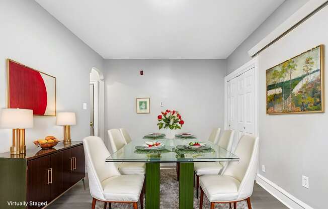 A dining room with a glass table and white chairs.
