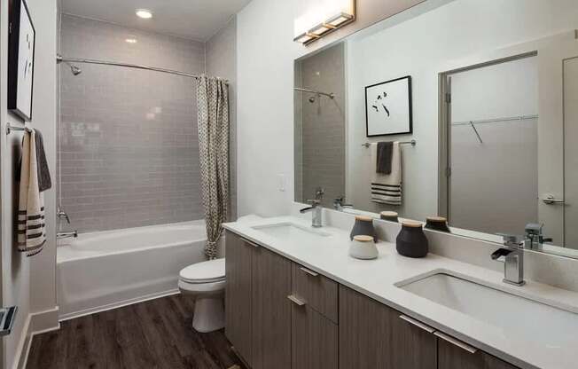 A bathroom with a white toilet, a bathtub with a shower curtain, a sink, a mirror, and a rug on the floor.