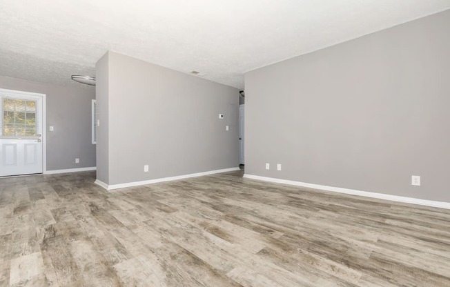 the living room and dining room of an empty house with vinyl flooring