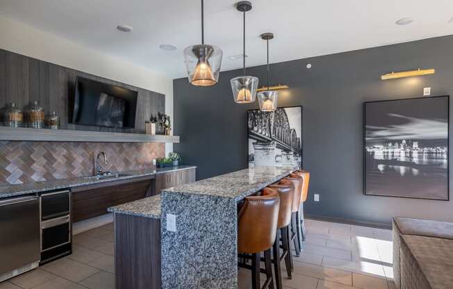 a kitchen with a long bar with chairs and a television