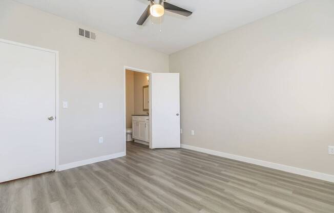 A room with a ceiling fan and light, two doors, and a cabinet in the background.