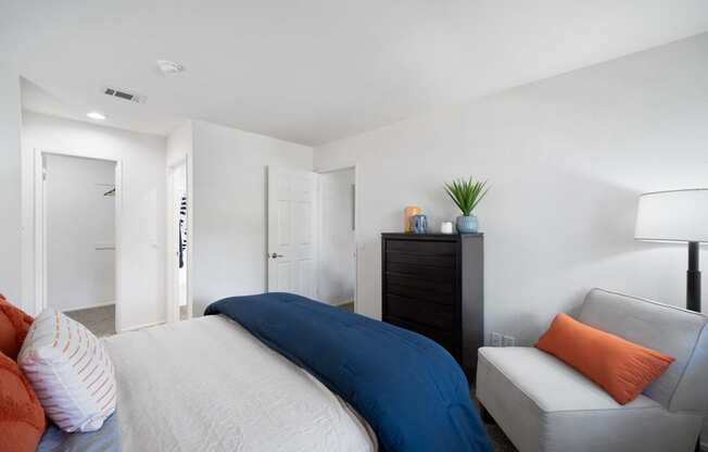a bedroom with a bed and a chair and a dresser