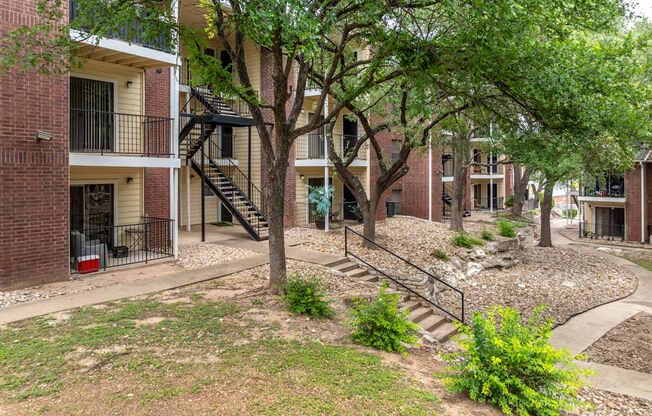 A tree in front of a brick building with a staircase.