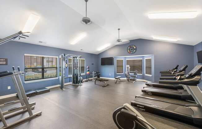 a gym with cardio machines and weights and a clock on the wall