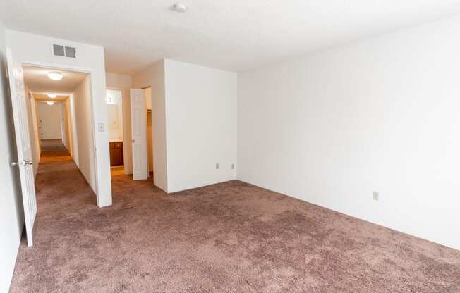an empty living room with white walls and carpet
