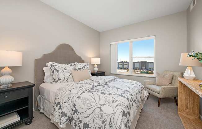 A bedroom with a large bed and a chair.