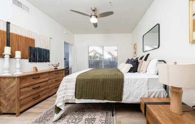 A bedroom with a bed, dresser, and ceiling fan.