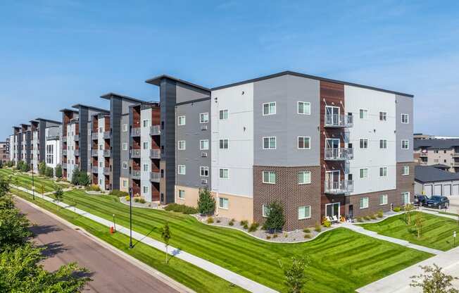 A row of modern apartment buildings with green lawns in front.