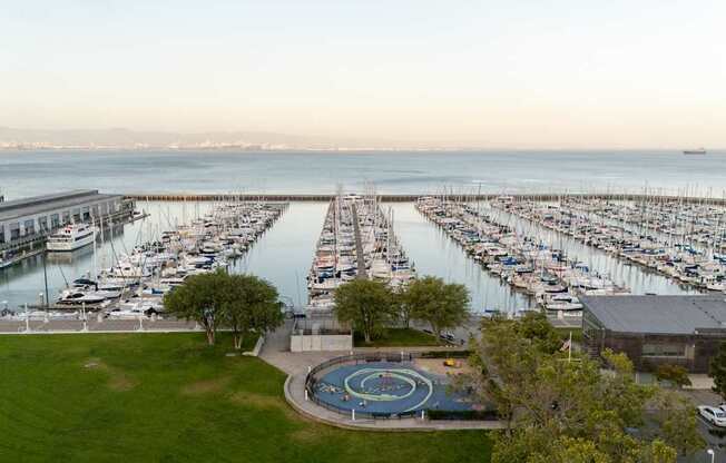 A marina with boats docked in the water and a circular fountain in the foreground.