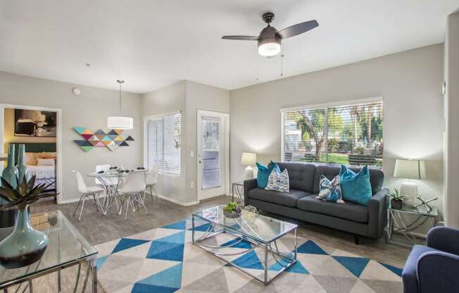 A living room with a grey couch and a glass coffee table.