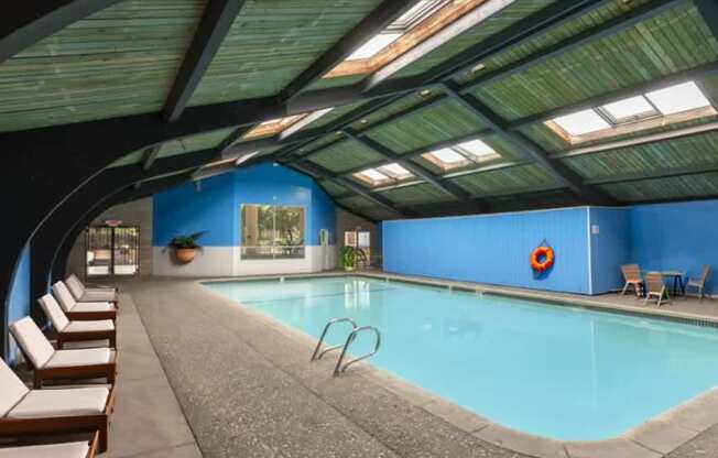 A large indoor swimming pool with sunroofs and lounge chairs.