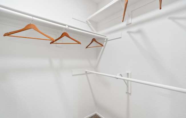 a walk in closet with white walls and white rods with hangers