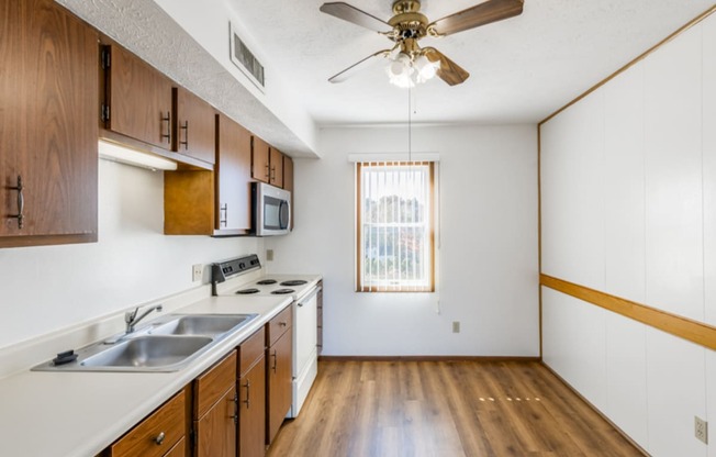 an empty kitchen with a ceiling fan and a sink