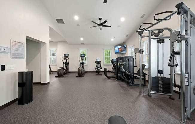 A gym with a variety of equipment including treadmills, weights, and a television.