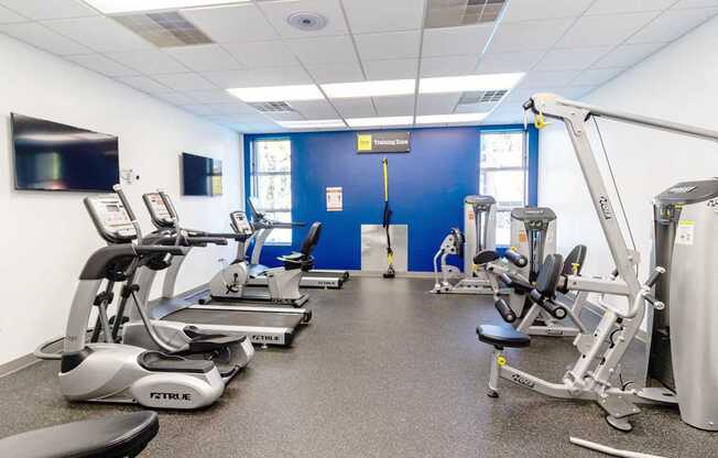 a gym with various exercise equipment and a tv